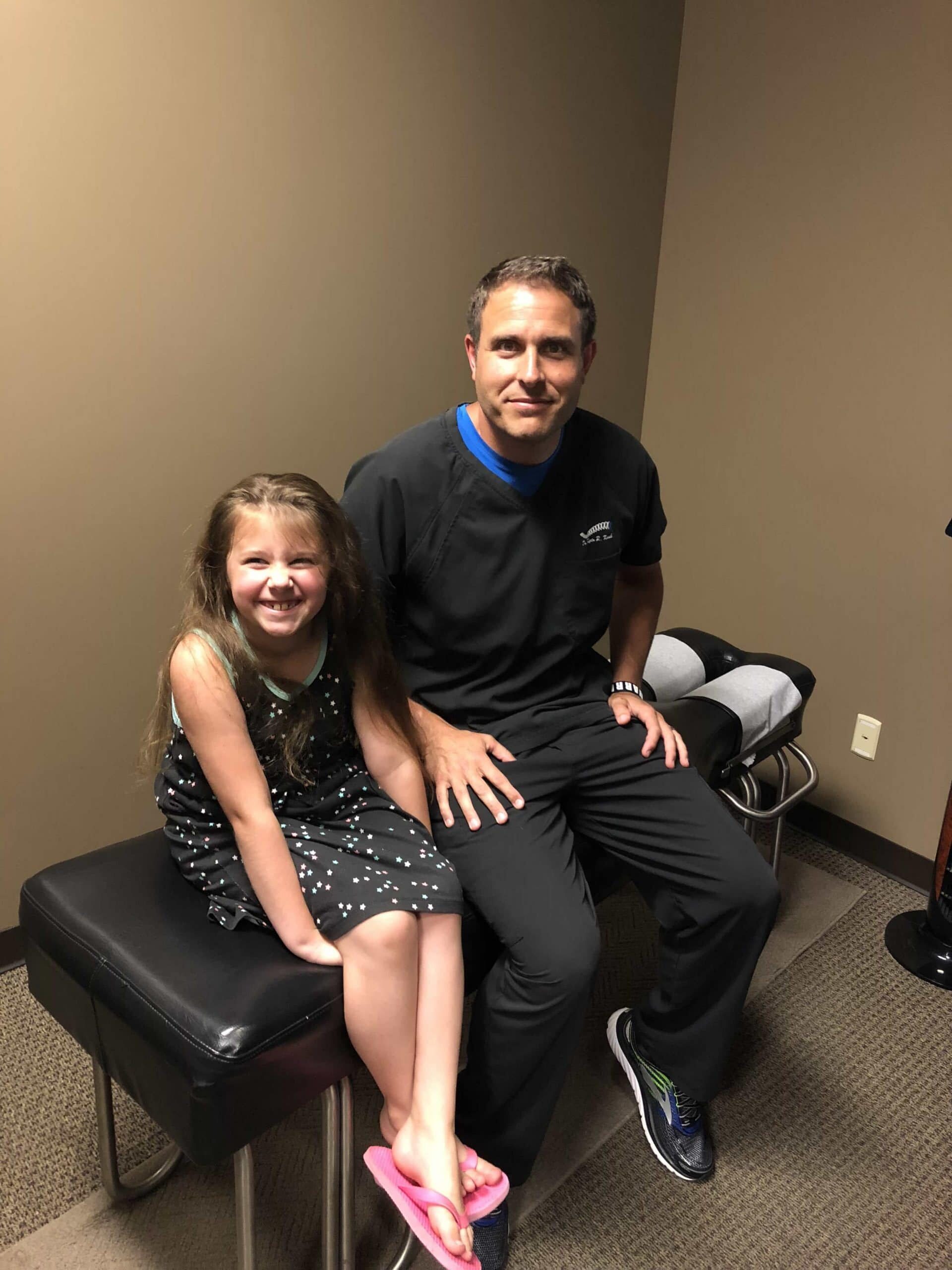 Photo of Dr. Kosak and a young girl sitting on a chiropractic table