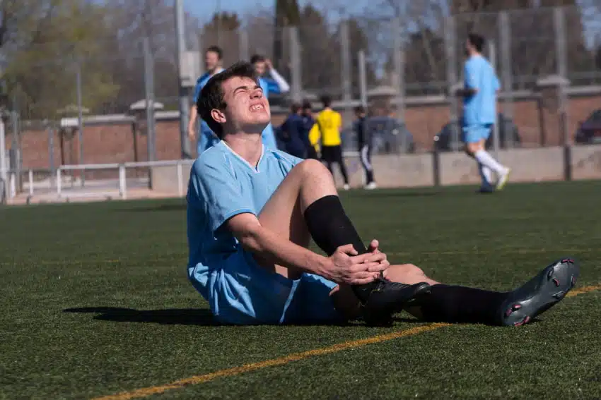 man holding suffers from sports injury while playing soccer